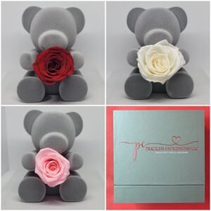 Gray flocked teddy bear holding a preserved rose, gift-boxed in a Priceless Expressions LLC box; rose available in red, pink, or white.