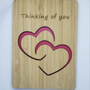 Wooden “Thinking of you” card with layered heart cutout design and pink accent backing, shown on a white background.